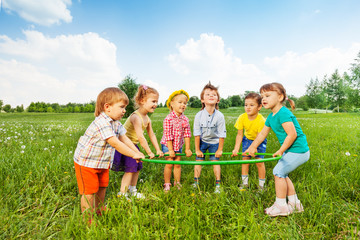 Smiling children holding one hoop together © Sergey Novikov