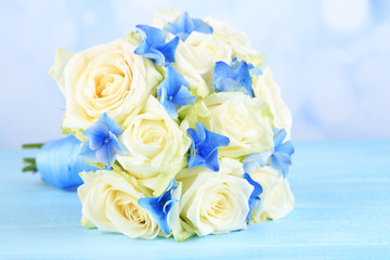 Beautiful wedding bouquet with roses on blue wooden table