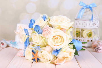 Beautiful wedding bouquet with sea decor on wooden table
