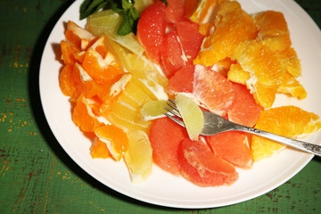 Sliced citrus fruits on plate, on wooden background