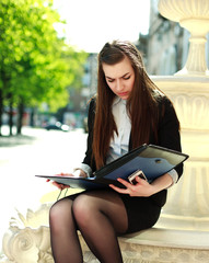 Obraz premium Young business woman working with a folder of documents sitting