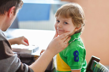 Father painting flag on face of little son