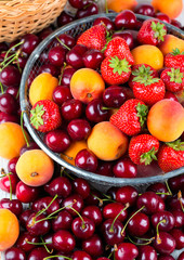 fresh berries and fruits in metallic basket on wooden surface