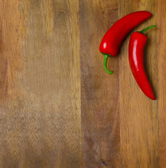 two red hot chili peppers on a wooden background