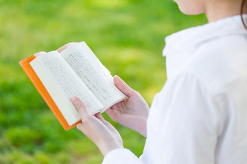 young asian woman reading book in the park