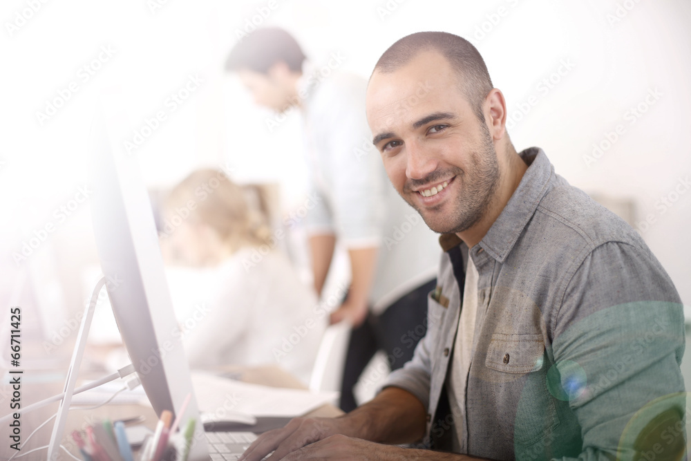 Aufkleber cheerful guy sitting in front of desktop computer