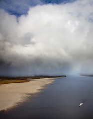 Great river with quickly motor boat under snow clouds