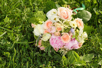 Beautiful bouquet of roses is on green grass at sunny summer day