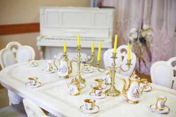 Table with set of porcelain dishes and candles