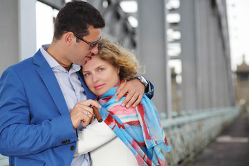 Stylish man with cigar embraces pregnant woman in white