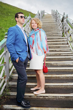 Happy pregnant woman in white and stylish man stand on stairs