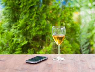 Glass of the white wine  and smartphone in the garden