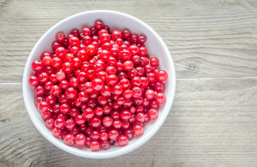 Bowl with fresh redcurrant on the wooden table