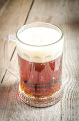 Mug with dark beer on the wooden table