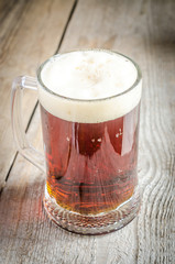 Mug with dark beer on the wooden table
