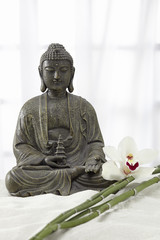 Buddha Statue mit Bambus und Orchideenblüte