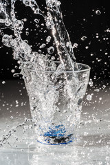 Obraz na płótnie Canvas Versamento acqua nel bicchiere in trasparenza