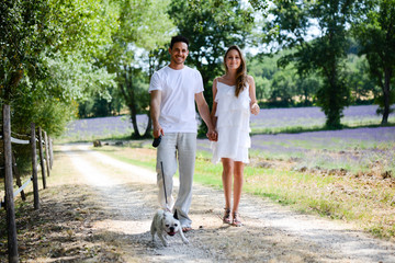 young happy man woman couple walking with dog summer vacation