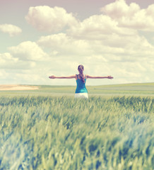 Faded retro style image of a girl in a wheat field