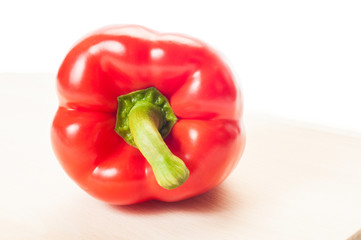 Closeup of a red pepper on wooden plate.