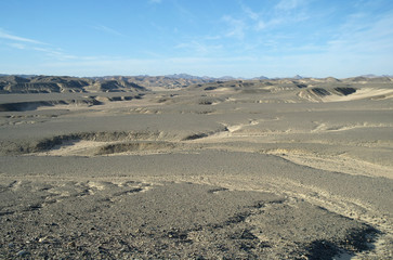 Fototapeta na wymiar Egyptian desert covered by black stones and blue sky.