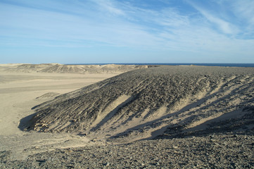 Egyptian desert covered by black stones and blue sky.