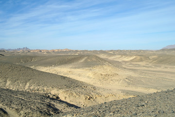 Fototapeta na wymiar Egyptian desert covered by black stones and blue sky.