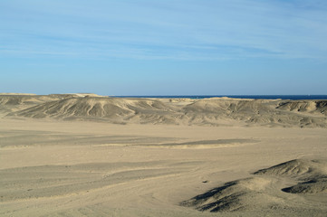 Egyptian desert covered by black stones and blue sky.