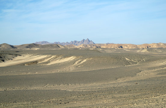 Egyptian desert covered by black stones and blue sky.