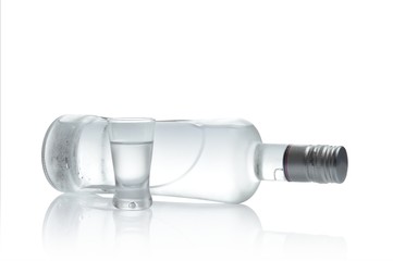 Bottle and glass of vodka lying isolated on white background