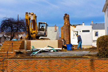 A large backhoe demolishes an old building