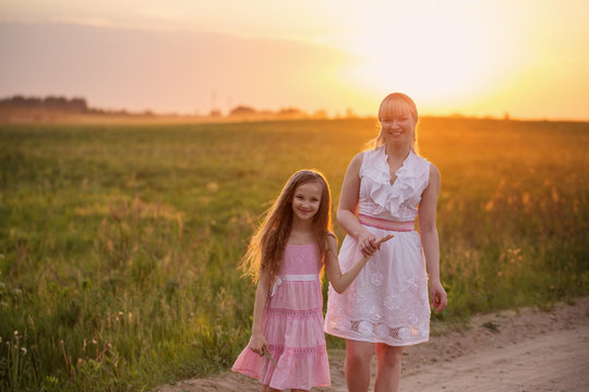mother and daughter walking by the road in the wheat field on su