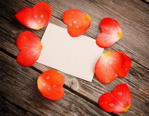 red petal with paper on wooden background