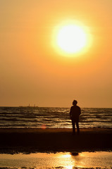 Silhouette man on beach with sunset sky background