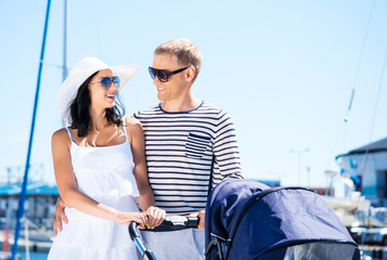 Young and attractive couple walking with a baby pram outdoor