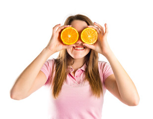 Girl with oranges in her eyes over white background