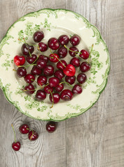 Plate with fresh cherries on the rustic table