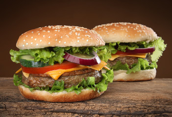 Two delicious hamburgers on wood background.
