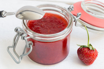 Erdbeermarmelade in einem Einmachglas auf Holz