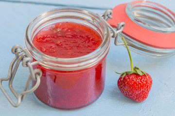 Erdbeermarmelade in einem Einmachglas auf blauem Holz