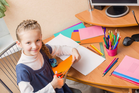 Girl with scissors cuts paper at home