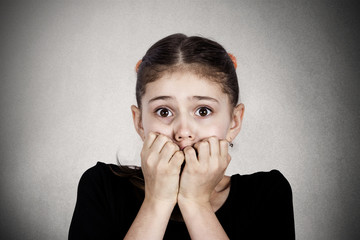 headshot scared, stressed little girl on grey wall background 