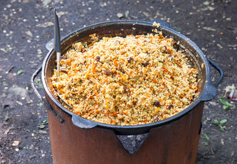 Cooking pilaf in a large cauldron outdoors