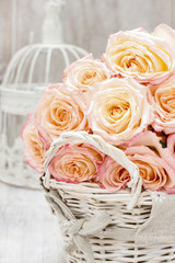 Wicker basket of roses on rustic wooden table.