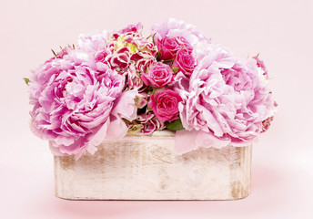 Pink peonies and roses in wooden box.