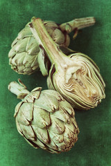 Obraz premium close up of a green fresh artichoke on a green background.