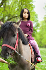 Little Asian girl sitting on a horse