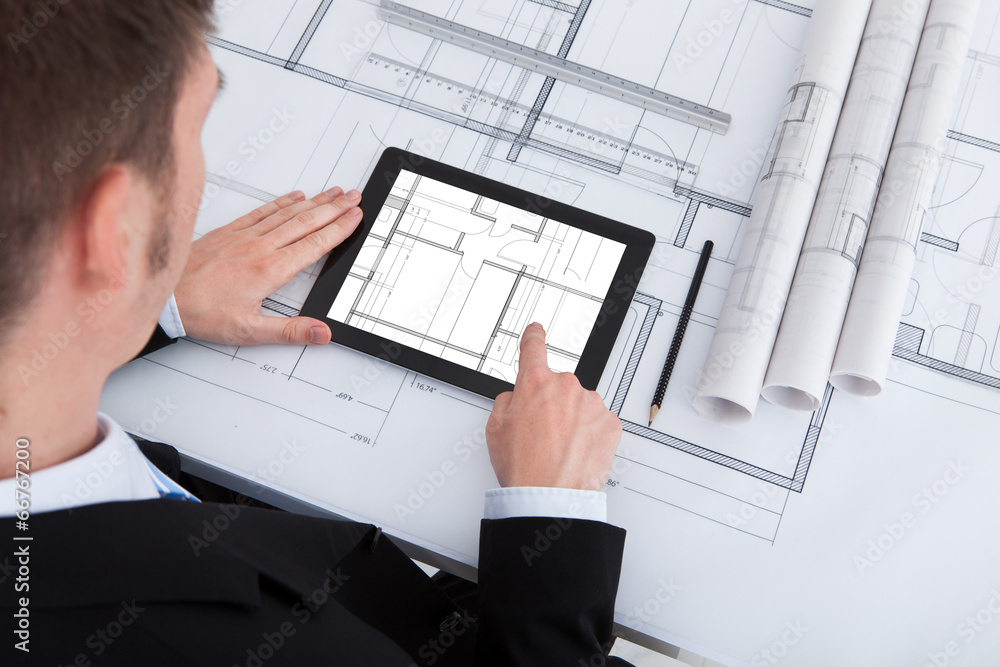 Poster architect using digital tablet on blueprint in office