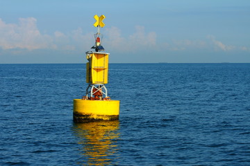 Floating yellow navigational buoy on blue sea