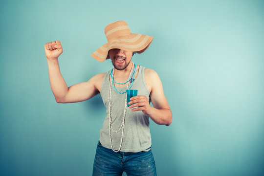 Happy young man wearing beach hat is drinking